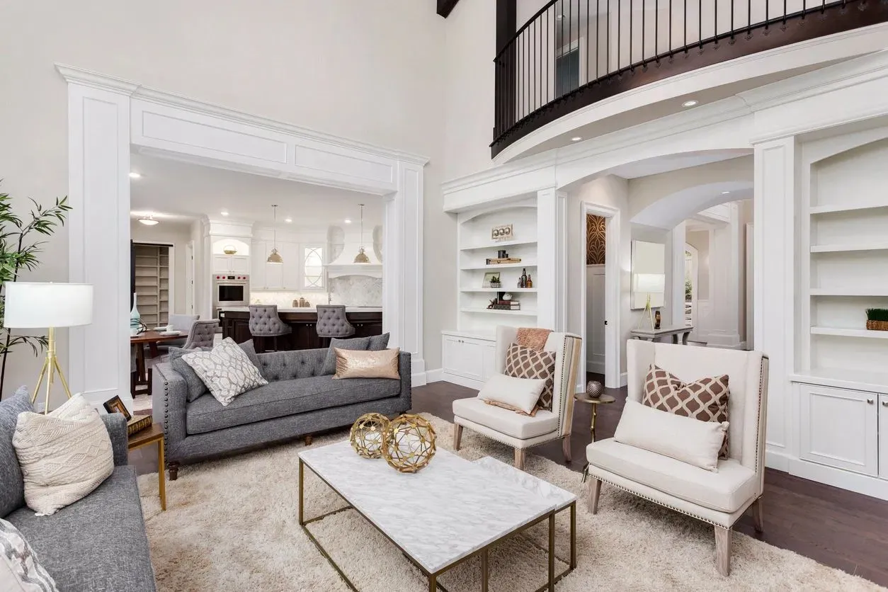 Elegantly staged neutral living room with built-in shelving and high ceilings